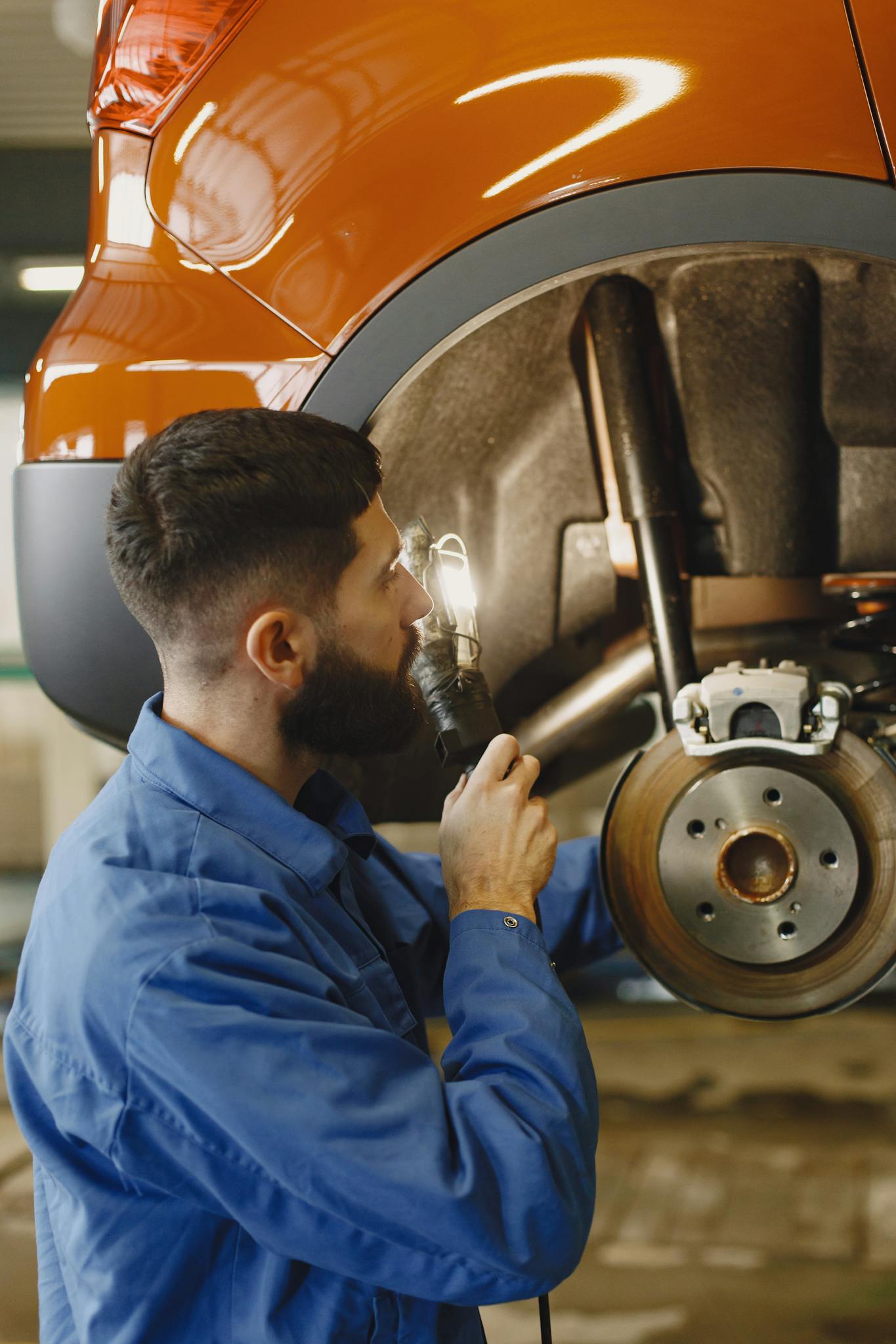 Auto mechanic conducting brake inspection at repair shop with focused attention.